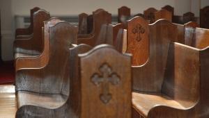 wooden pews with a cross engraved on their side.