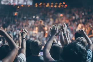 Group of people in auditorium with hands raised worshiping