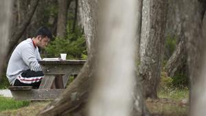 Man sitting at picnic table in park reading