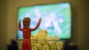 Jesus action figure in front of popcorn bowl facing TV