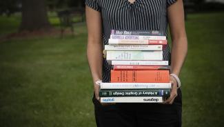 Person holding massive stack of textbooks