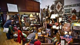 Woman shopping at antique store full of furniture and random knickknacks