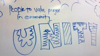 Whiteboard with "People to value prayer in community. Unity" written in large blue letters