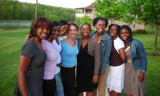 Group photo of Black and White female students in front of woods and pond