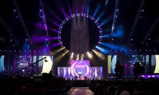 Stage of Urbana with huge ring of colorful lights, bright stage pieces, and shadowy background 