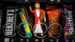 Jesus action figure sitting in vending machine next to candy bars