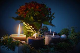 Four candles in a wreath surrounding a spring of poinsettia