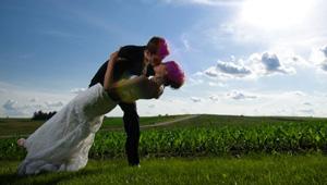 Bride and groom kissing in front of cornfield