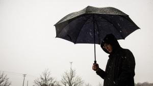 Person wearing raincoat, holding umbrella