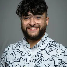 Domenic smiling in a white and black shirt and glasses