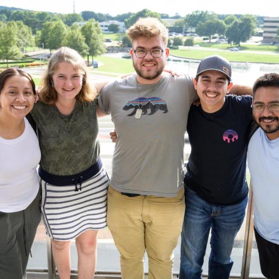 Five students with arms around each other, smiling