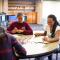 Three students gathered at table doing manuscript Bible study with pile of colored pencils and marked up manuscript sheets