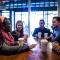 A group of students gathered around a table, drinking coffee, and talking