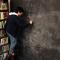 Student standing on ladder writing equation on enormous chalkboard