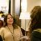 Group of four women talking and laughing in hotel hallway outside of conference session