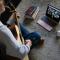 Student sitting on floor playing guitar leading virtual worship