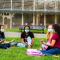 Group of students gathered outside sitting in grass singing