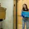 Two students moving into dorm, holding cardboard boxes