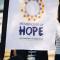 A white sign reading "Messengers of Hope: The University in God's Story"