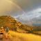 Two people hiking up a trail with cloudy sky and rainbow