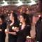 Group of students wearing black holding candles with much larger group in the background in stadium seating