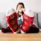 Woman sitting on couch wearing red Christmas socks propped up on table holding mug