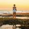 Young man standing beside tide pool at sunset