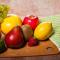 cutting board with fruit such as an orange, apple, lemon, grapes, and others. A cutting knife lies next to it