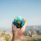 Hand holding small globe against mountain landscape