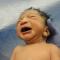 Closeup of newborn crying held by doctor