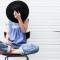 woman sitting cross-legged with a wide-brim hat covering her face