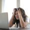 Woman cradling head in frustration, staring at computer