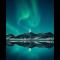 Green and blue Northern Lights shimmering above mountain and lake landscape