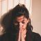 a young woman praying with her hands folded in front of her face