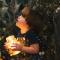Child holding jar full of fireflies staring up into sky