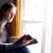 a woman reading a Bible next to a sunlit window