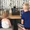 three small children sitting at a countertop using a computer