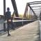 Man in jogging clothes stretching leg, leaning on railing on bridge