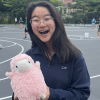 Sam smiling and holding stuffed lamb toy named Gerald (the unofficial InterVarsity mascot).