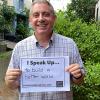 Man smiling and holding a sign that says "I speak up...to build a better world"