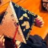 hands holding a graduation cap that reads "To the ends of the earth" on top