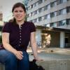 a female student sitting on a fountain in front of a dormitory building