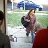 Student walking up the sidewalk to greet parents standing in the doorway
