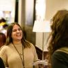 Group of four women talking and laughing in hotel hallway outside of conference session