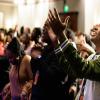 Group of students at conference worshiping, raising hands and singing