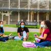 Group of students gathered outside sitting in grass singing