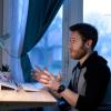 Young male staff sitting at desk having Zoom call on laptop