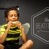 Young boy in bee costume sitting, eating sandwich with the words "The Beatitudes" in the background.