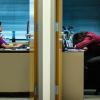 Two offices side by side with doors open. One woman is typing at her computer while the woman in the next office has her head down on the desk.