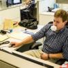 a man sitting in a cubicle blowing a bubble with gum